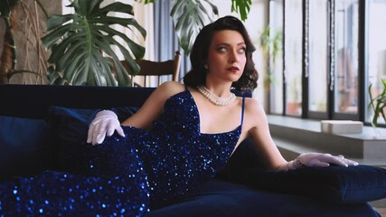 sexy woman fashion model posing in blue long dress evening gown white gloves old style. Glamour Retro lady beauty girl girl lies on stylish sofa. Wavy black hair holiday concept themed party new year - Powered by Adobe