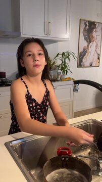 menina lavando lou&ccedil;as na cozinha 