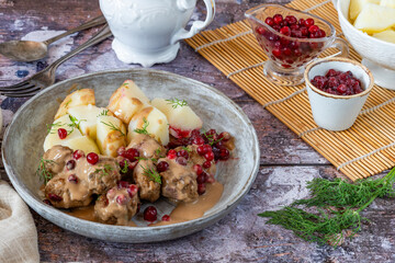 Traditional Swedish meatballs in creamy sauce with boiled potatoes and lingonberries