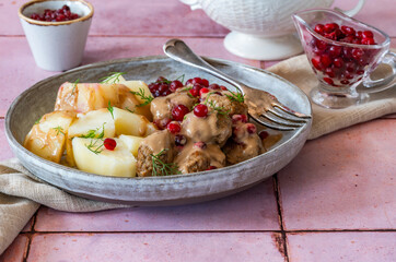 Traditional Swedish meatballs in creamy sauce with boiled potatoes and lingonberries