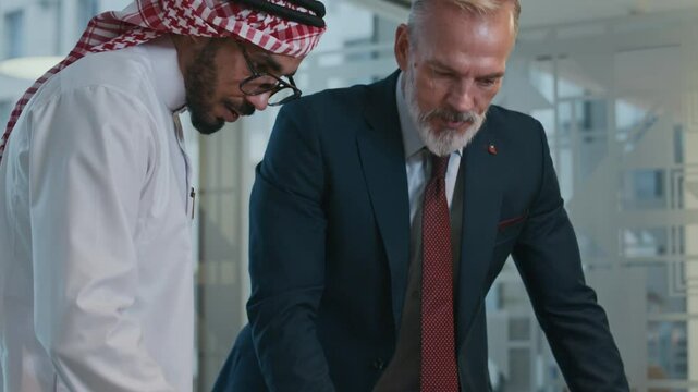 Tilt up shot of bicultural male entrepreneurs using laptop while communicating at office space