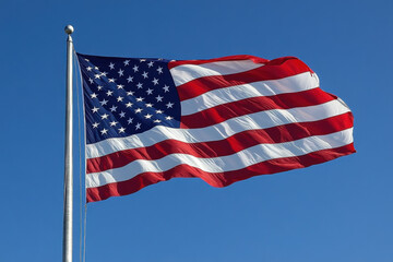 Obraz premium An American flag flies proudly in the wind, against a clear blue sky.
