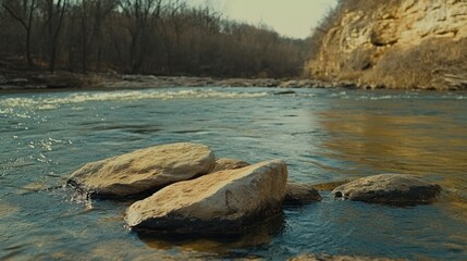 Rocks sit in a flowing river next to a rocky cliff edge