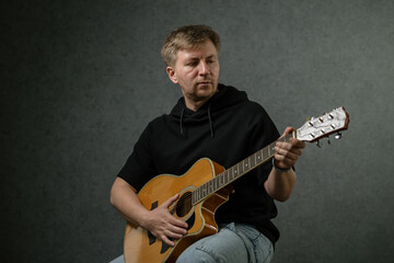 Obraz premium Man with guitar in room with gray background