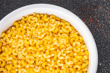 Macaroni pasta raw coquillette appetizer dish organic product fresh tasty gourmet food background on the table rustic food top view copy space