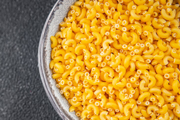 Macaroni pasta raw coquillette appetizer dish organic product fresh tasty gourmet food background on the table rustic food top view copy space
