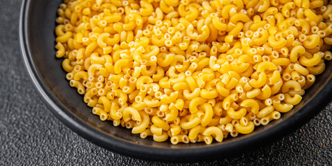 Macaroni pasta raw coquillette appetizer dish organic product fresh tasty gourmet food background on the table rustic food top view copy space