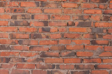 Grunge background of orange wall made of bricks bonded with cement of abandoned old building.