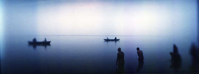 Panoramic view of people taking a ritual dip in a river, Ganges River, Varanasi, Uttar Pradesh, India.