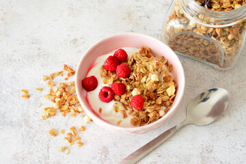 flat lay with Granola with yogurt and fresh raspberries in a pink bowl