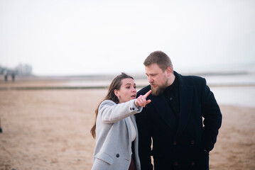 Caucasian couple discussing on beach: young male and female in winter attire