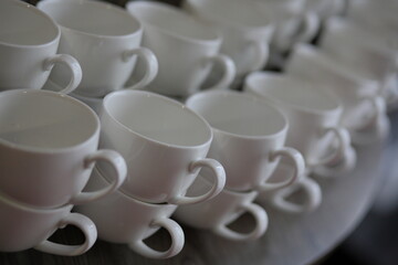 Neatly stacked white porcelain coffee cups in rows