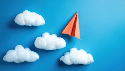 Orange paper airplane flying among fluffy white clouds in blue sky