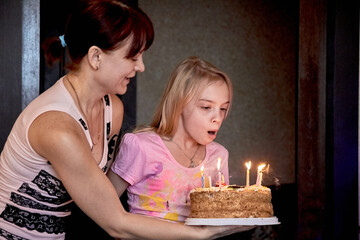 A girl tries to blow out the flame of a candle