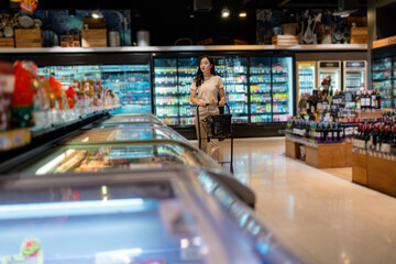 Young woman pushing shopping cart in supermarket looking for groceries