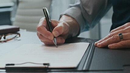 Close up shot of hands of unrecognizable businessman signing contract at table in office
