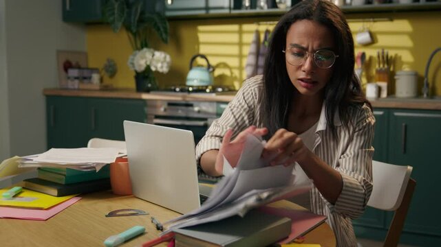 Stressed frustrated busy Latina Hispanic woman anxious businesswoman teen girl female high school student at home kitchen searching documents on table messy papers work laptop mistake problem stress