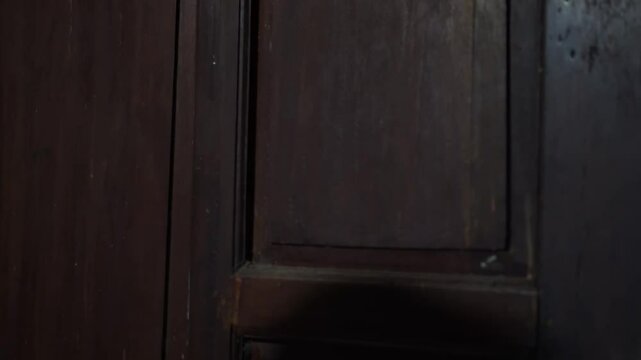 a misterious hand knocking on a door at night. The hand of a man in the dark is knocking on the door. scary at night concept
