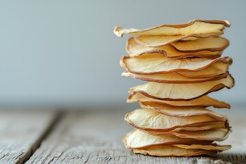 A side view of an accurate stack of dried thin apples slices, wood, copyspace on the left