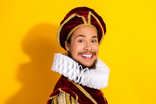 Portrait of a smiling man in a regal costume with a ruff collar against a vibrant yellow backdrop