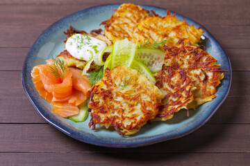 Hash browns with smoked salmon, cucumbers and yogurt. Vegetable fritters, latkes, potato cakes. Vegetable pancakes