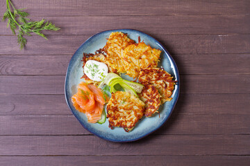 Hash browns with smoked salmon, cucumbers and yogurt. Vegetable fritters, latkes, potato cakes. Vegetable pancakes. High angle view