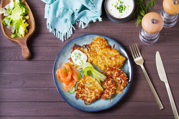 Hash browns with smoked salmon, cucumbers and yogurt. Vegetable fritters, latkes, potato cakes. Vegetable pancakes. High angle view