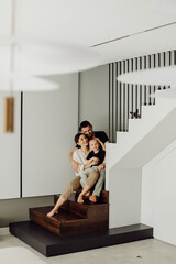Happy family relaxing together on modern staircase in minimalist home