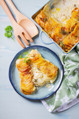 Potato and onion gratin on blue plate. Scalloped potatoes or potato bake. View from above, top view