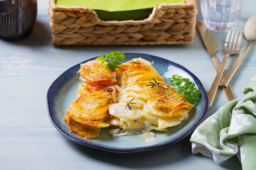Potato and onion gratin on blue plate. Scalloped potatoes or potato bake