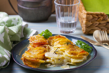 Potato and onion gratin on blue plate. Scalloped potatoes or potato bake
