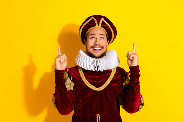 Smiling man dressed as medieval noble against yellow background, wearing velvet costume, historical...
