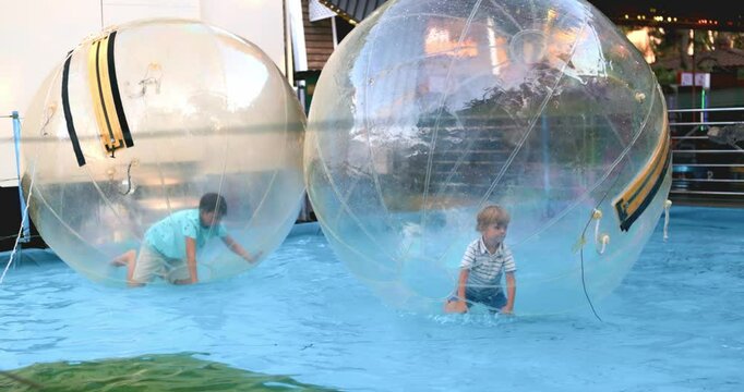 Children playing inside inflatable water walking ball in slow motion
