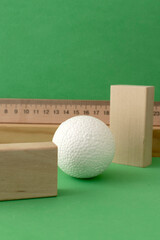 Still life with wooden blocks and a a plastic foam ball on green background