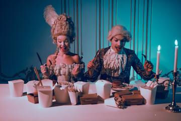 A couple dressed in baroque costumes enjoys modern fast food under neon lighting
