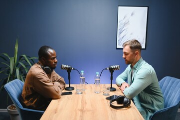 Man recording podcast using high tech microphones to interview guest, ensuring flawless video and...