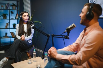Female podcaster in headphones interviewing man guest using microphone, smiling, recording and...