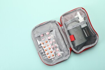 First aid kit on light blue background, top view. Space for text