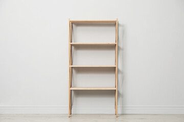 Empty wooden shelving unit near light grey wall indoors