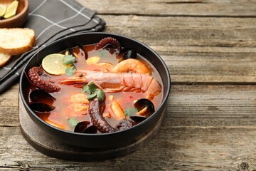 Delicious seafood soup in bowl on wooden table, closeup. Space for text