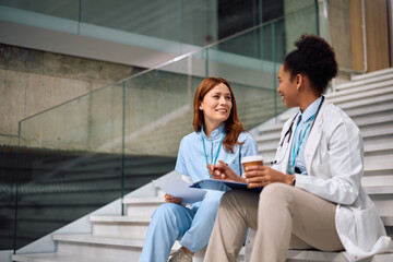 Happy female doctor talking during their coffee break at medical clinic.