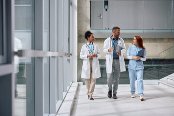 Group of doctors communicating while walking through hallway at the clinic.