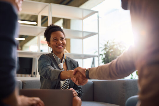 Happy black insurance agent greeting her client on a meeting in the office.