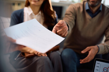 Close up of financial advisor offering contract to a couple during a meeting in the office.
