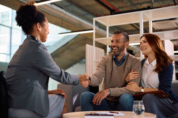 Happy couple coming to an agreement with their insurance agent in the office.