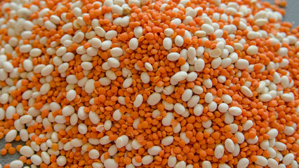 Red lentils and white beans scattered on a black background. Selective focus.