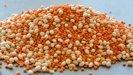 Red lentils and white beans scattered on a black background. Selective focus.