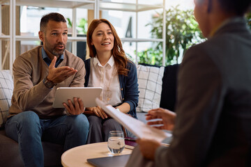 Mid adult couple using touchpad during a meeting with insurance agent in the office.