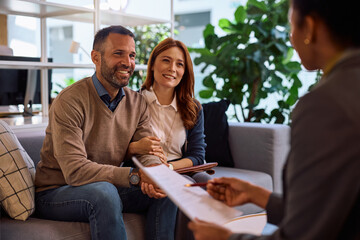 Happy couple having a meeting with their financial advisor int he office.