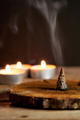Incense Cone Burning on Wooden Base With Candles Glowing Softly